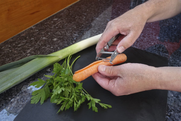 Southern German cuisine, preparation of vegetables, carrot, leek, parsley, raw carrot peel, paring knife, asparagus peeler, men's hands, cutting board, vegetarian, vegan, healthy, food photography, studio, Germany