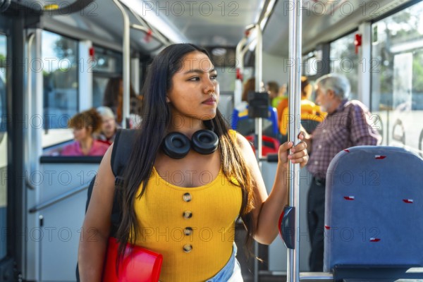 Young woman passenger holding a handrail inside a public bus, wearing headphones and a backpack, looking away while traveling, representing urban daily commute and student life