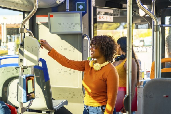 Happy young woman passengers using a smart card on an electronic validator, paying for a journey on public transport, demonstrating modern urban commuting solutions