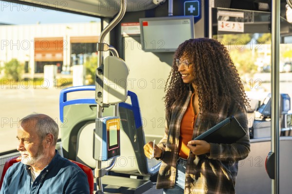 Young woman smiling while validating her transit card on a public bus, traveling in a city environment during her daily commute, with an older man sitting nearby