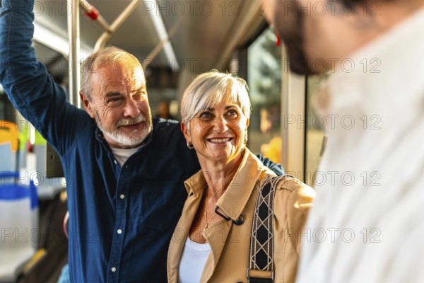Happy senior couple standing on a city bus, smiling and chatting with another passenger while holding the handrail, enjoying a bright, relaxed commute together