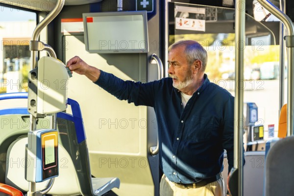Senior man inserting his travel ticket into a modern validator device inside a public transportation bus, representing daily commute, urban travel, and independent mobility