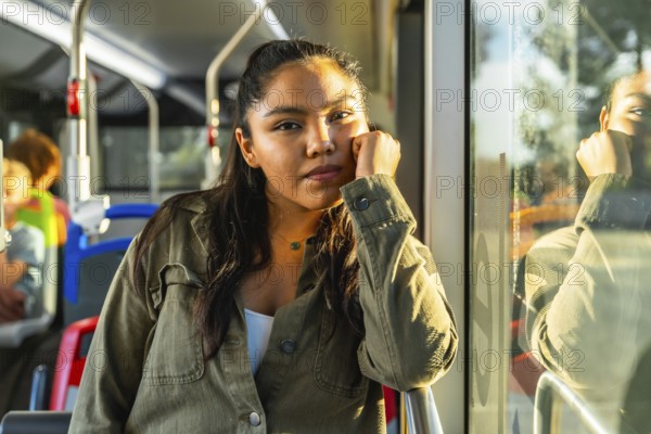 Young woman riding public transport contemplating and looking at camera while warm sunlight reflects on the bus window, creating a thoughtful atmosphere