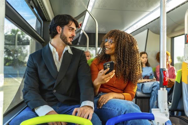 Diverse couple traveling on a public bus, the woman showing content on her smartphone to the man while they are talking and smiling, enjoying their daily commute together