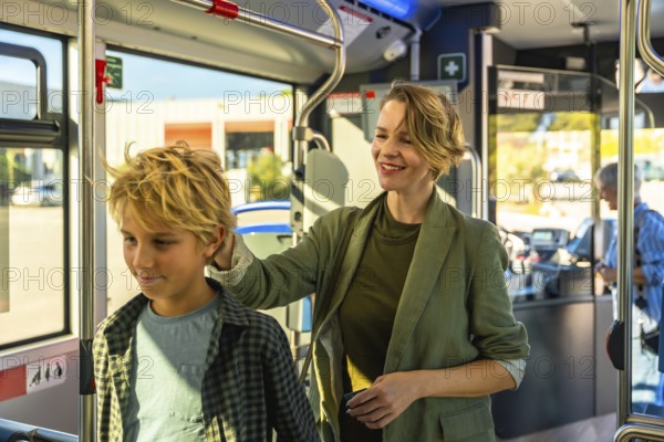 Mother and son share a warm moment on a modern city bus, woman resting her hand on his shoulder as they smile, enjoying reliable, sustainable urban transit together