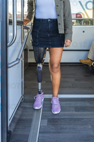 Woman with a prosthetic leg standing inside a public transport bus, holding onto a handrail, representing concepts of disability inclusion, urban mobility, and accessibility for amputees