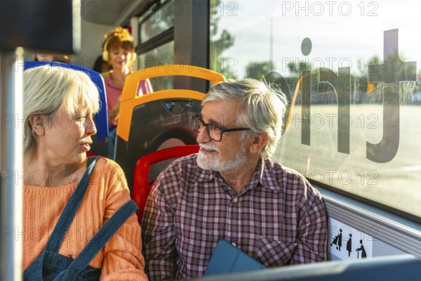 Senior couple chatting and smiling as they travel together on a city bus, enjoying companionship and independence during their daily commute through urban life