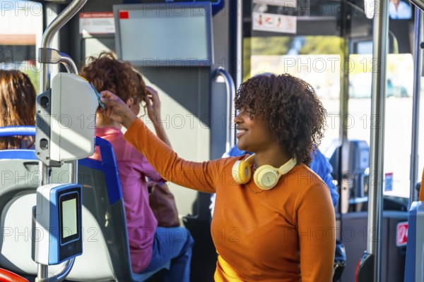 Smiling woman with headphones validating a contactless travel card on a modern electronic validator inside a city bus, commuting comfortably using public transit technology and routine