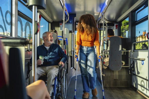 Mature man in wheelchair and young woman using crutches riding inside a modern public transportation bus, demonstrating accessibility and urban mobility for individuals with mobility impairments