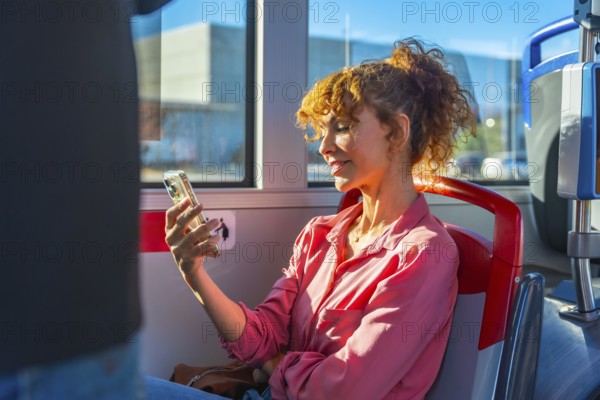 Woman on a city bus smiling while scrolling smartphone, enjoying digital content and staying connected with friends and family during her daily commute in bright daytime light