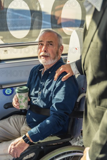 Senior man in a wheelchair receiving assistance from another person, highlighting support and accessibility during public transport travel and daily life