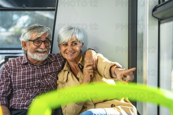 Happy senior couple on a bus, smiling and pointing out the window while enjoying a relaxed city journey together, sharing warmth, curiosity and travel companionship