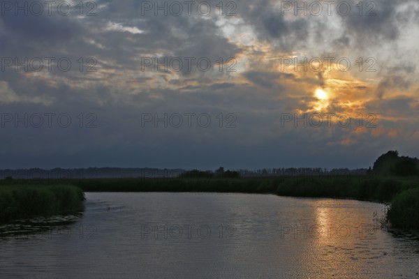 Cloudy sky at sunset over a river with slight reflection, Peenetal nature park Park, Mecklenburg-Western Pomerania, Germany