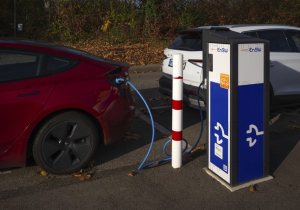 Parking lot with gas pump, EnBW charging station for electric cars, charging station, e-charging station, e-mobility, charging cable leads into two vehicles, e-car, pictogram, logo, Stuttgart, Baden-Württemberg, Germany