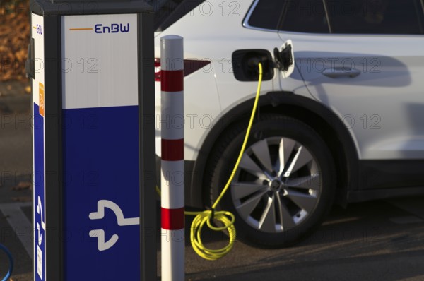 Parking lot with gas pump, EnBW charging station for electric cars, charging station, e-charging station, e-mobility, charging cable leading into a vehicle, e-car, pictogram, logo, Stuttgart, Baden-Württemberg, Germany