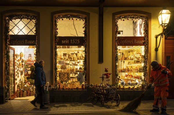 At Christmas time, a passerby walks past a souvenir shop in Frankfurt's New Old Town, while an FES employee sweeps the street, Neue Altstadt, Frankfurt am Main, Hesse, Germany