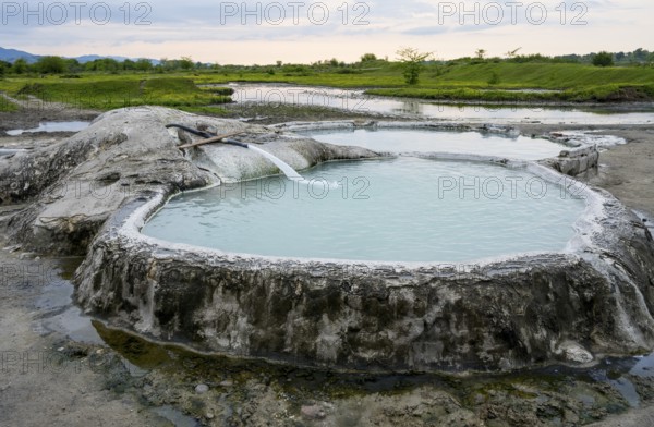 Hot spring pool in natural landscape with vast meadows and cloudy sky, springs of Amaghleba, Dikhashkho Sulfur Geyser, hot sulfur springs of Wani, Vani, Rioni River, Imereti region, Georgia