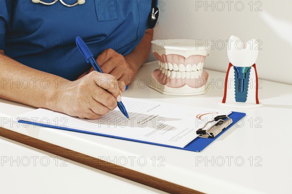 A dentist in a blue uniform studies patient information and prepares for treatment in a modern dental office