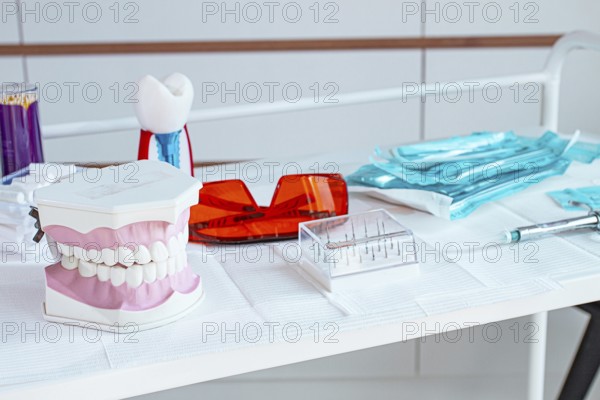 Various instruments, dental models, and hygiene items are laid out on the table in the dental office. natural light