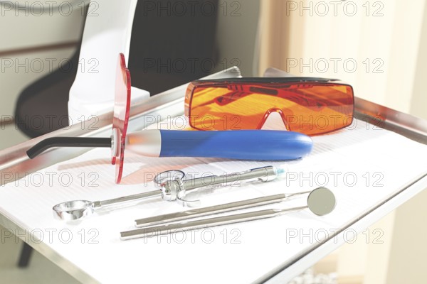 On the tray are various dental instruments, a model dental implant and bright orange safety glasses, ready for use in clinical dental settings