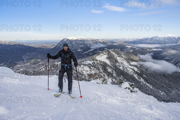 Happy ski tourer climbing to Längenfelderkopf, view of mountain landscape in winter, Wetterstein Mountains, Garmisch-Partenkirchen, Bavaria, Germany