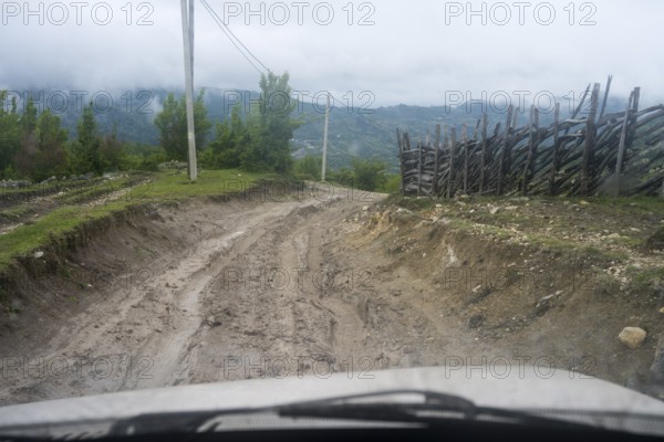 Muddy dirt road in a rural area leads through nature, four-wheel drive Lada, Imereti region, Imereti, Georgia