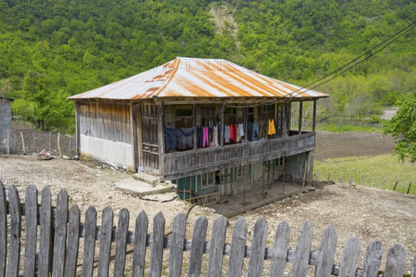 Old wooden house with veranda and colorful laundry, rural area, Imereti region, Imereti, Georgia