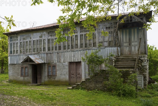 Old wooden house with lots of windows surrounded by trees in the countryside, Imereti region, Imereti, Georgia