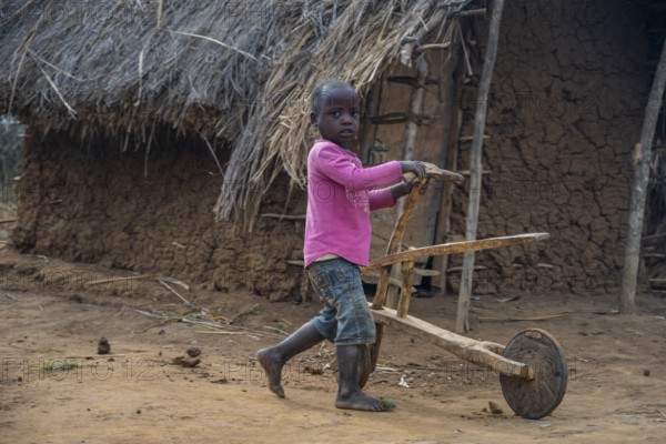 Child playing with a self-made wooden balance bike, in a Sadaani village, Tanga, Tanzania