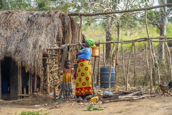 Mother and child in front of a simple traditional clay hut in a Sadaani village, Tanga, Tanzania
