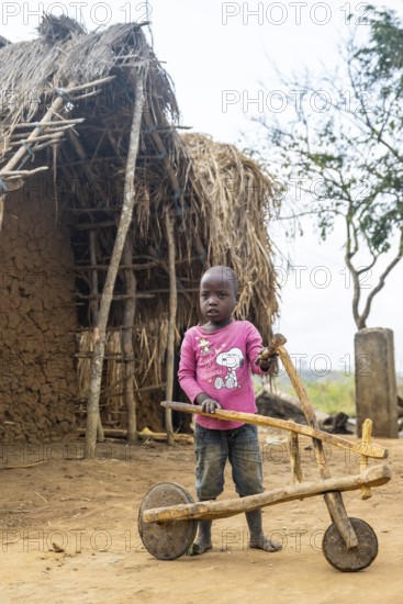 Child playing with a self-made wooden balance bike, in a Sadaani village, Tanga, Tanzania