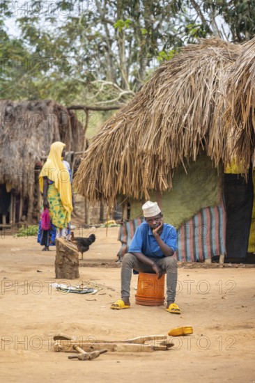 Man sitting on an upturned bucket in a Sadaani village, Tanga, Tanzania