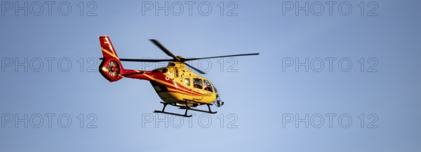 Rescue helicopter flying against a blue sky, Tyrol, Austria