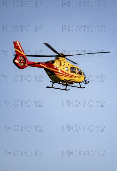 Rescue helicopter flying against a blue sky, Tyrol, Austria