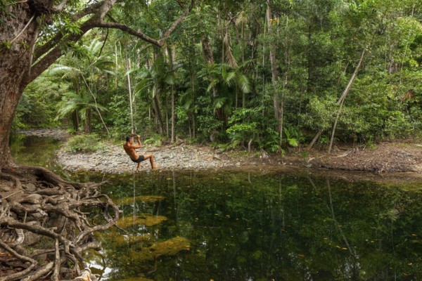 Man swings on a rope in the swimming pool at Emmagen Creek in Daintree National Park, Cape Tribulation, Queensland, Australia
