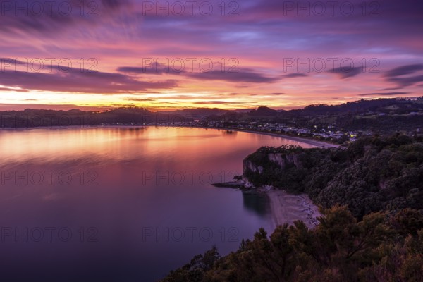 Landscape with sea and sandy beach in New Zealand. View of Lonely Bay and Cooks Beach from Shakespeare Cliff in the morning at sunrise. Colored clouds. Cooks Beach, Coromandel Peninsula, Waikato, New Zealand