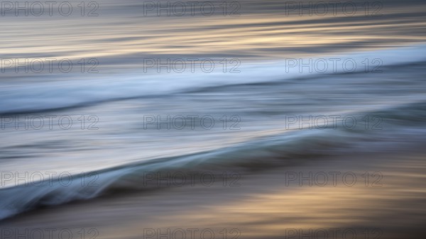 Sea waves in the evening light. Long exposure with ICM (Intentional Camera Movement), blurred