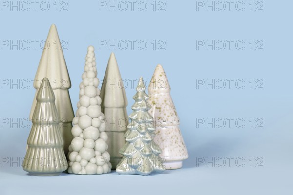 Ornamental light green ceramic Christmas trees on blue background with copy space