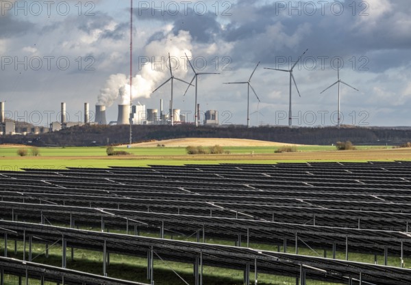 86.5 MW peak open space photovoltaic systems, from RWE, with over 141, 000 solar modules, on a side strip, along the A44 motorway near Jüchen, at the timber triangle, recultivated open-cast mining site, in the background RWE Neurath lignite power plant, wind farm, North Rhine-Westphalia, Germany