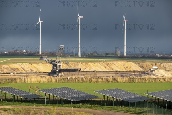 Parts of an 86.5 MW peak open-air photovoltaic system, from RWE, with over 141, 000 solar modules, on a side strip, along the A44 motorway near Jüchen, on the timber triangle, recultivated open-cast mining site, in the background RWE settling in the open-cast mine, fill the pit with debris from the Garzweiler open-cast mine, Jüchen wind farm, North Rhine-Westphalia, Germany
