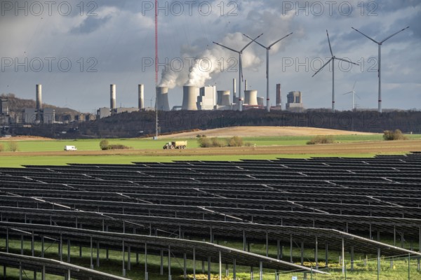 86.5 MW peak open space photovoltaic systems, from RWE, with over 141, 000 solar modules, on a side strip, along the A44 motorway near Jüchen, at the timber triangle, recultivated open-cast mining site, in the background RWE Neurath lignite power plant, wind farm, North Rhine-Westphalia, Germany