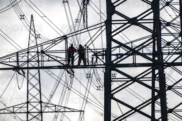 Work on a 380 kV high-voltage overhead line, new construction, along the A57 motorway, near Meerbusch, workers on the boom of the high-voltage pylon, North Rhine-Westphalia, Germany