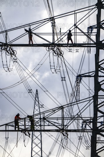 Work on a 380 kV high-voltage overhead line, new construction, along the A57 motorway, near Meerbusch, workers on the boom of the high-voltage pylon, North Rhine-Westphalia, Germany