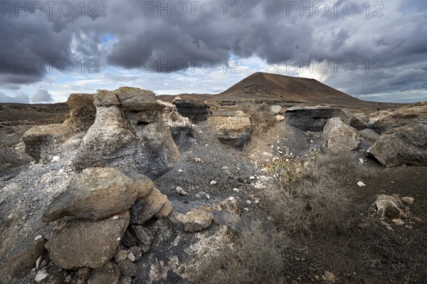 Eroded rock formations in volcanic landscape with dramatic cloudy skies, Ciudad Estratificada or Los Roferos, Antigua Rofera de Teseguite, Lanzarote, Canary Islands, Spain