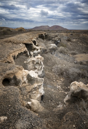 Eroded rock formations in volcanic landscape with dramatic cloudy skies, Ciudad Estratificada or Los Roferos, Antigua Rofera de Teseguite, Lanzarote, Canary Islands, Spain