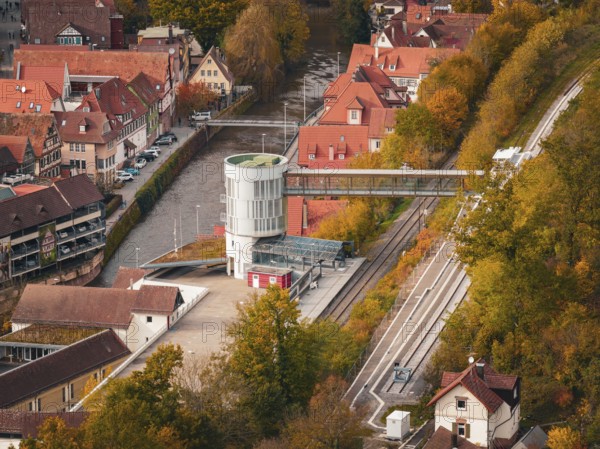 Station building with bridge across river, surrounded by autumn leaves and traditional houses, Calw, Black Forest, Germany
