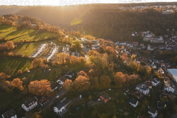 Sunset over a landscape with houses, trees and a parking lot, in autumn, Calw, Black Forest, Germany