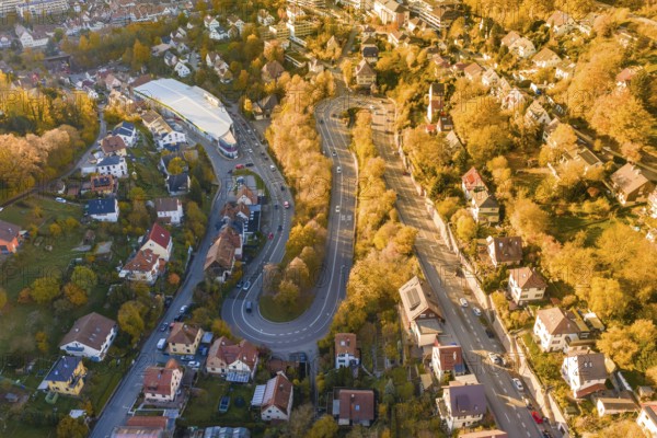Aerial view of a winding road surrounded by houses and autumn trees in a town, Calw, Black Forest, Germany