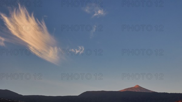 Striped clouds in the evening sky over a distant volcano in soft light, UNESCO World Heritage Site, Teide National Park, Teide National Park, Tenerife, Canary Islands, Spain