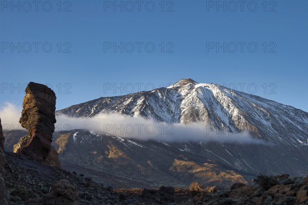 Snow-covered Teide, majestic snowy mountain with rugged rocks in sunlight and clouds above, UNESCO World Heritage Site, Teide National Park, Parque Nacional del Teide, Tenerife, Canary Islands, Spain